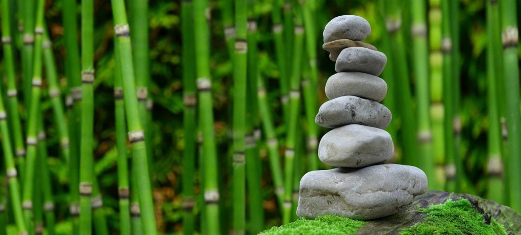 Imagem de um lindo jardim zen feito com bambus e várias pedras de tamanhos diversificados, feito para meditar.