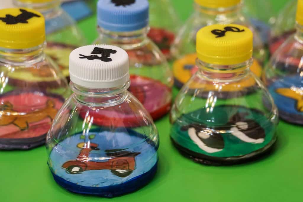 Imagem de um brinquedo reciclado feito de garrafa pet. São vários cofrinhos coloridos para guardar moedas.
