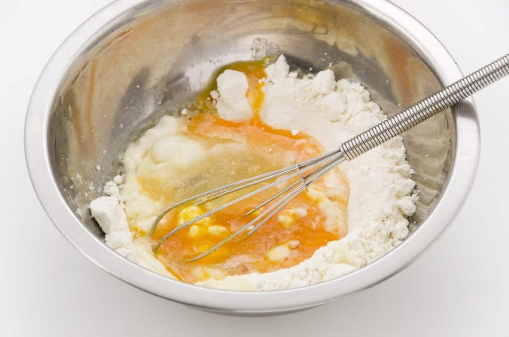 Imagem de uma bacia de inox e dentro dela ovos misturado com amigo de milho para fazer hidratação no cabelo.