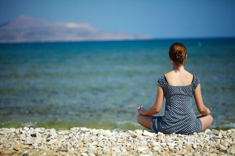 Mulher jovem sentada na praia desfrutando de um momento de paz