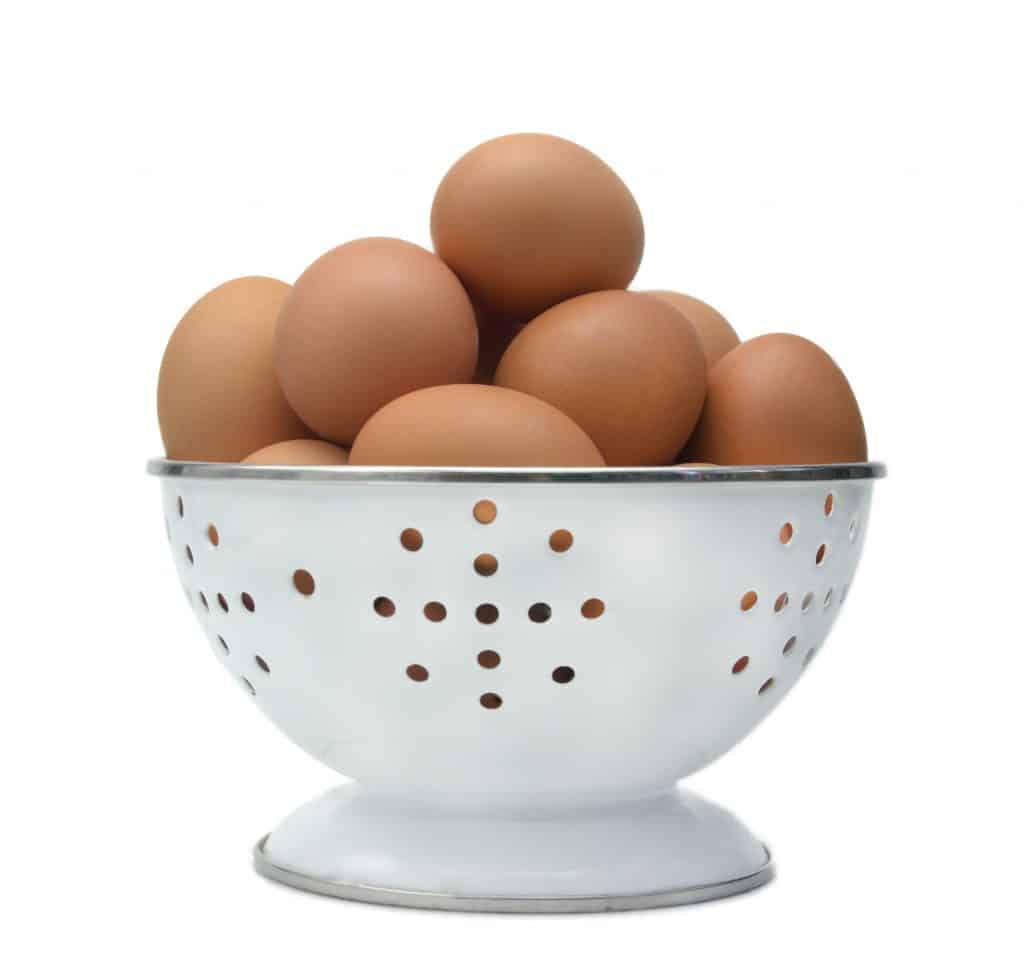Imagem de um escorredor de macarrão cheio de ovos vermelhos para serem usados em receitas de creme de hidratação.
