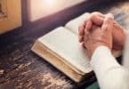 Mulher segurando uma Bíblia nas mãos e orando