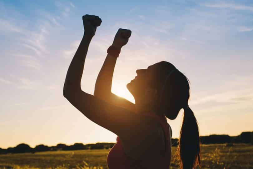 Mulher levantando os braços para comemorar o sucesso