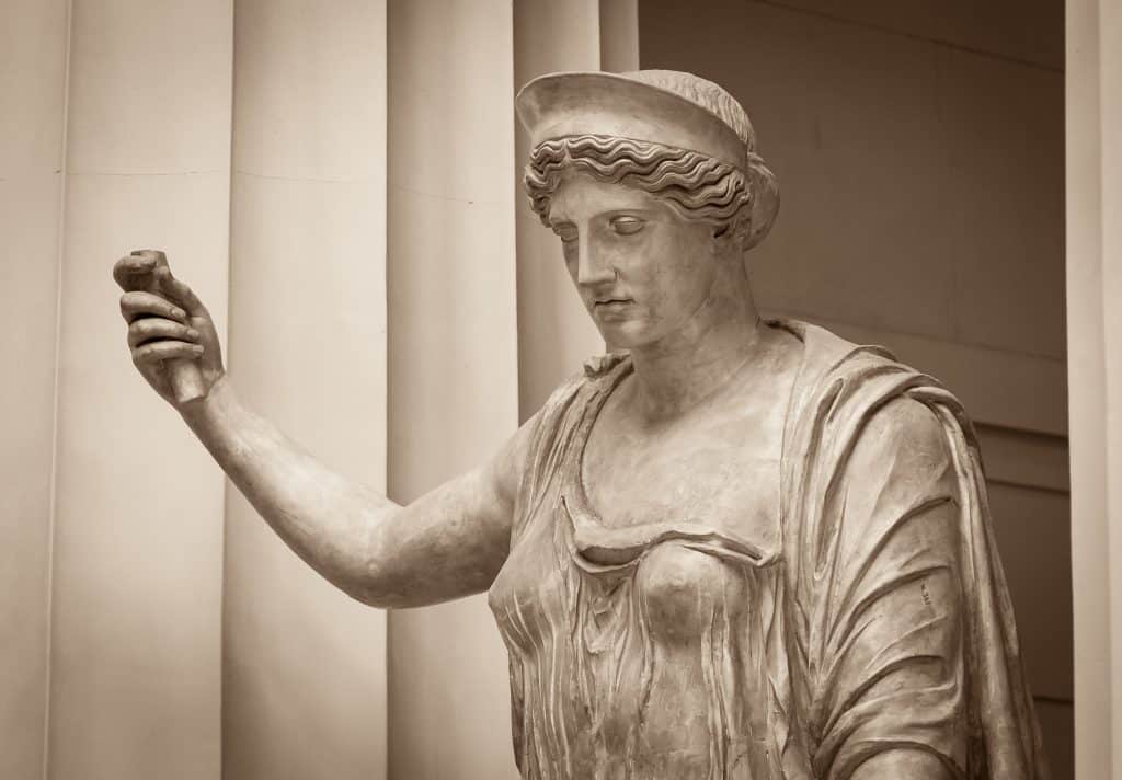 Imagem da estátua de uma mulher representando a deusa Hera. Em uma das mãos ela segura um objeto.