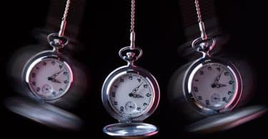 Imagem preto e branco de três relógios de pêndulos usados para serem usados em sessões de hipnoterapia.