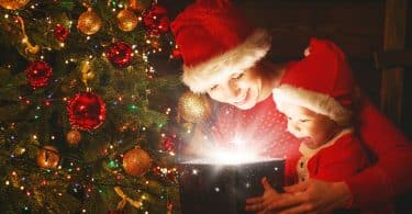 Mãe e filho bebê com um presente mágico da árvore de Natal