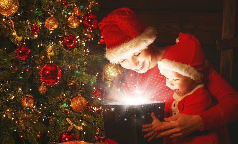 Mãe e filho bebê com um presente mágico da árvore de Natal