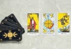 Imagem de cartas de tarot em cima de uma mesa, algumas viradas para cima e o baralho virado para baixo