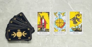 Imagem de cartas de tarot em cima de uma mesa, algumas viradas para cima e o baralho virado para baixo