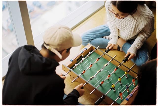 Homem e mulher brancos jogando mini pebolim.