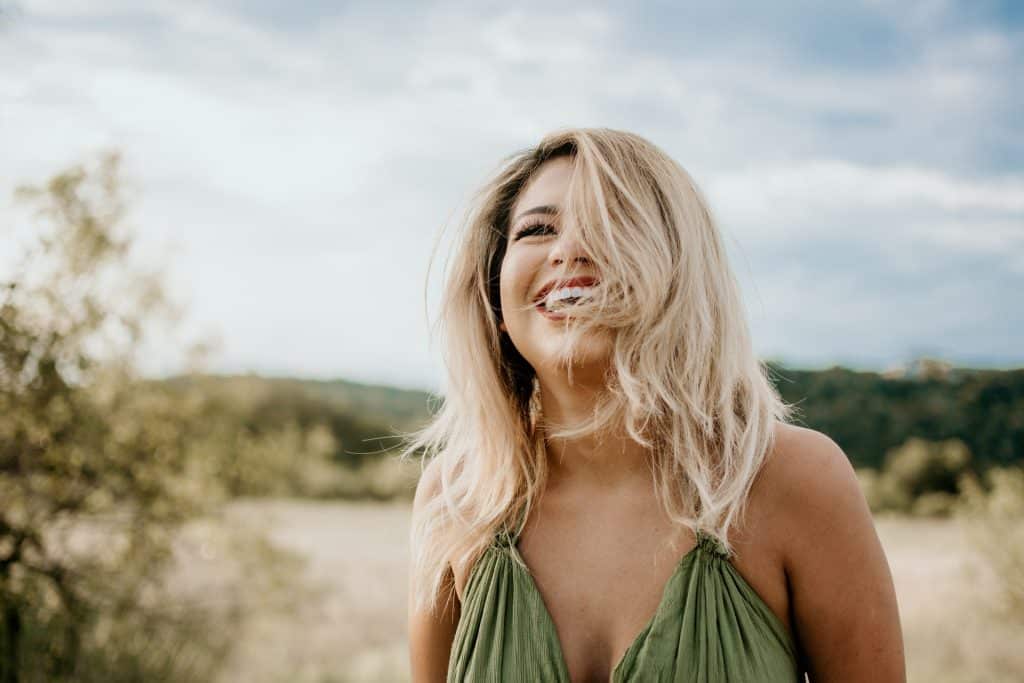 Mulher branca de cabelos curtos e loiros ao vento, com expressão sorridente.