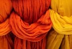 Imagem de três tecidos nas cores laranja claro, laranja avermelhado e amarelo para serem utilizados para hamonizar o ambiente.