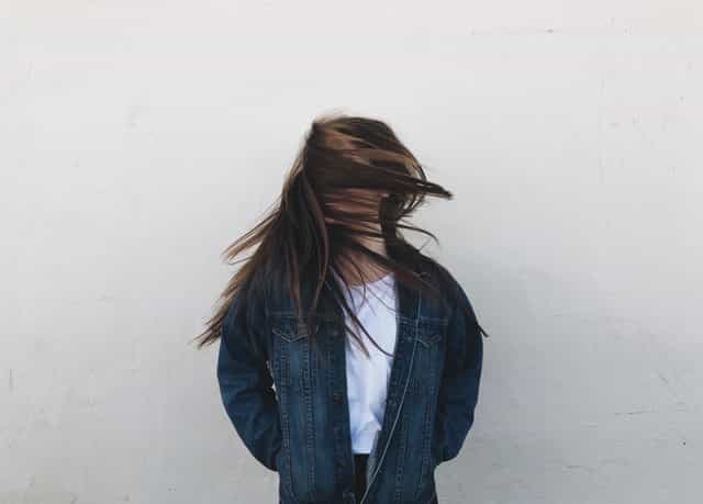 Jovem branca balançando a cabeça, com cabelo no rosto.