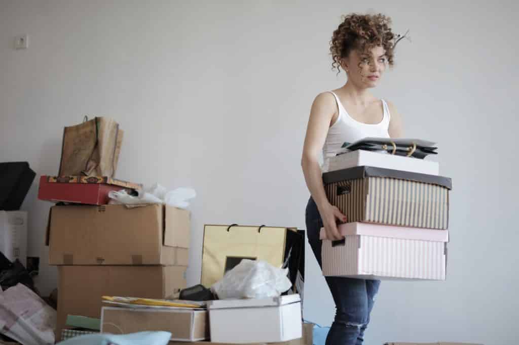 Mulher segurando caixas com mais caixas ao fundo representando organização