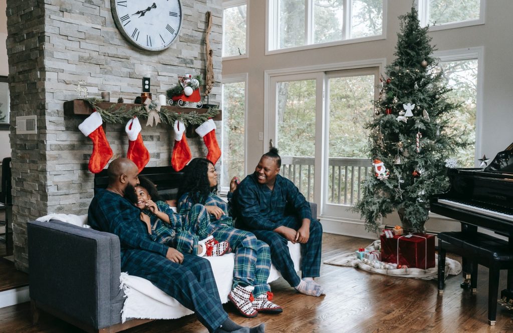 Família conversando sentados no sofá ao lado da árvore de natal