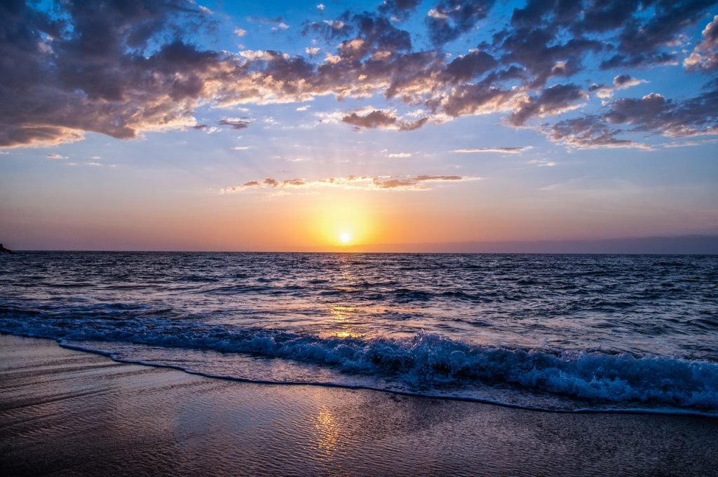 Paisagem do mar com o pôr do sol ao fundo.
