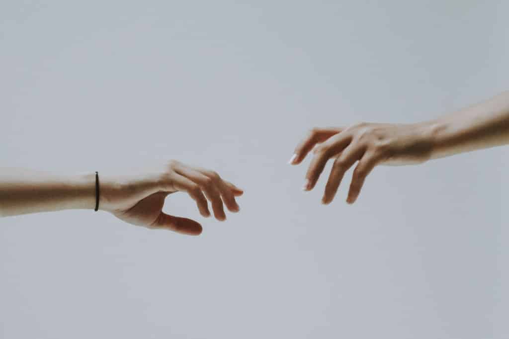 Duas mãos próximas, na tentativa de se tocarem.