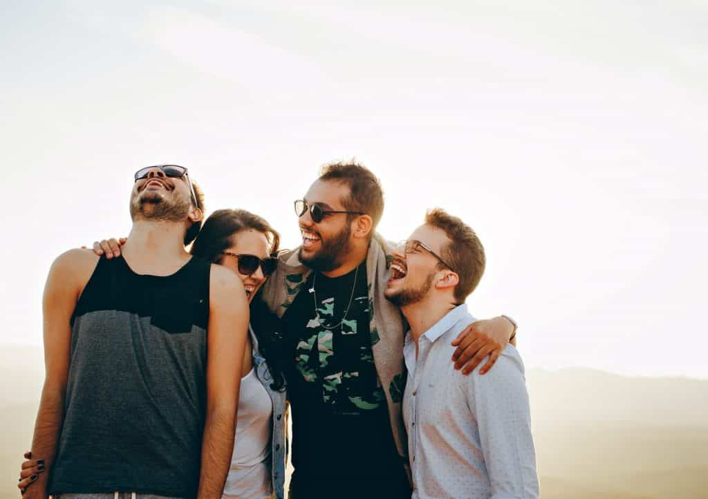 Quatro amigos se abraçando enquanto estão rindo 