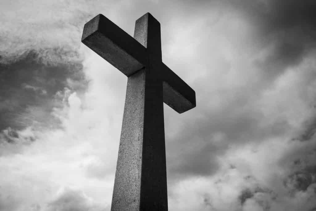 Cruz em preto e branco e céu com nuvens.