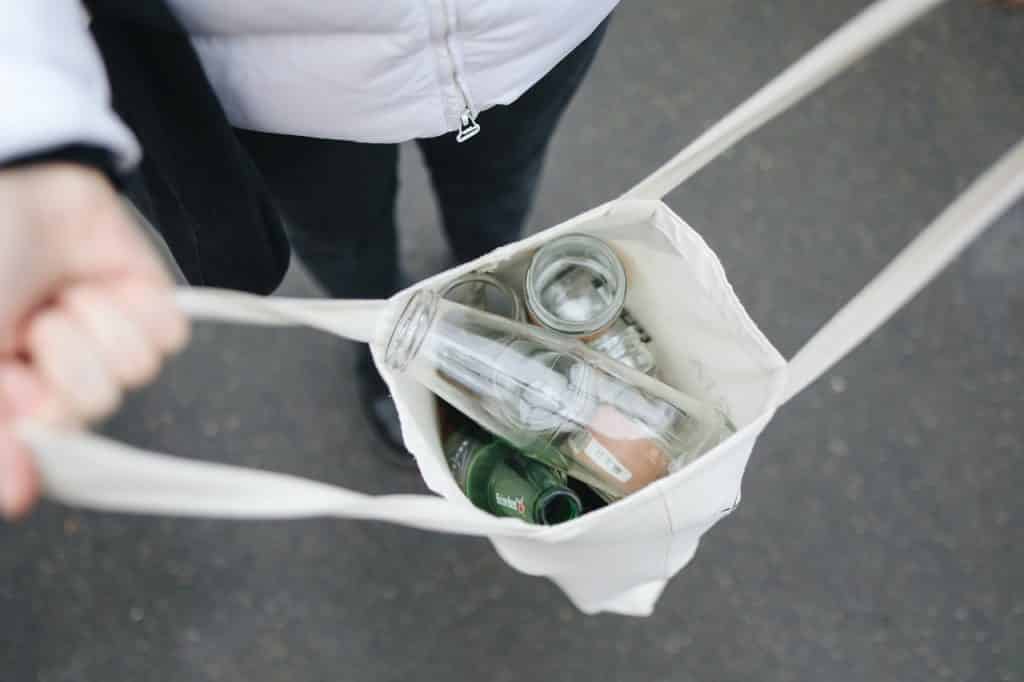 Sacola aberta com itens vazios e recicláveis em seu interior.