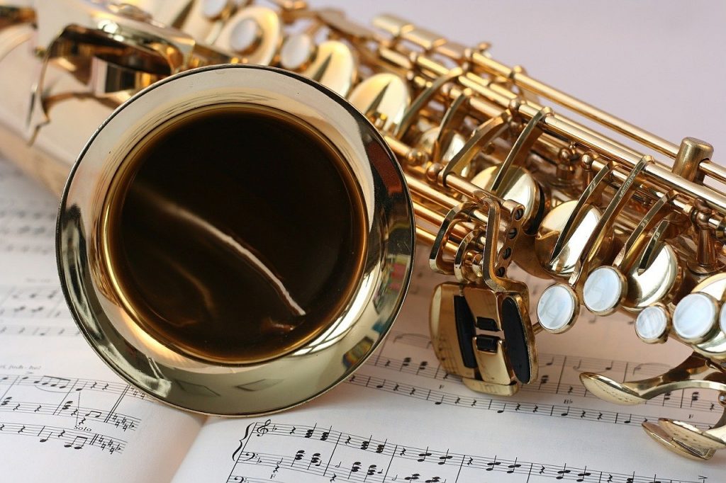 Imagem de um saxofone dourado sobre um caderno de música.