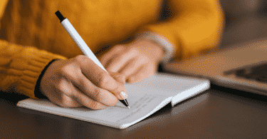 Pessoa escrevendo algo em páginas de um caderno