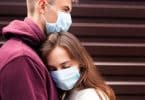 Jovem casal se abraçando com máscara de proteção facial na cidade desde novo coronavírus.