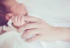 Bebê segurando dedo da mãe