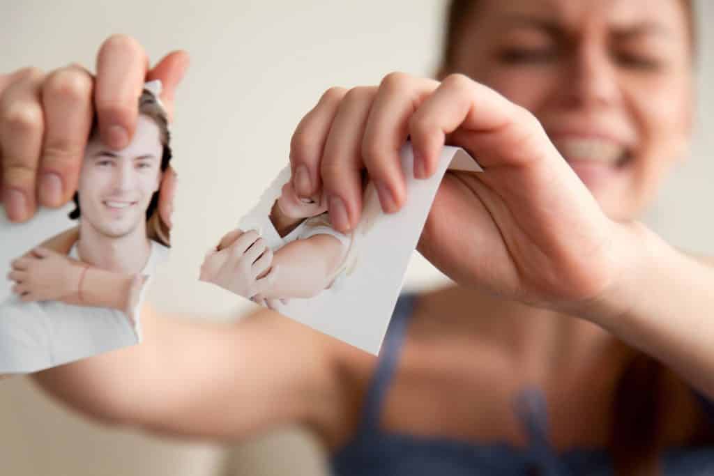 Mulher branca rasgando foto de casal depois de sonhar com traição.