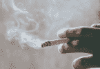Pessoa segurando cigarro entre os dedos