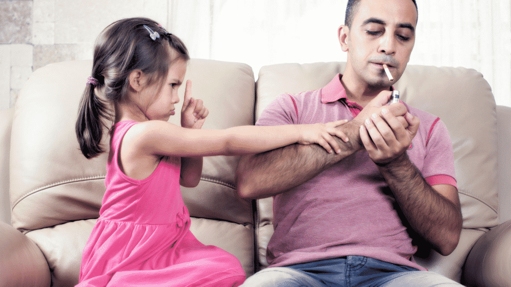 Homem acendendo cigarro e criança ao lado tentando impedir