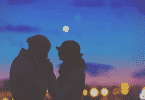Silhueta de casal de mãos dadas com a vista noturna de uma cidade atrás