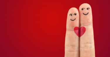 Imagem de fundo vermelho e em destaque dois dedos representando um casal. Um deles a mulher e o outro o homem. O que une os dedos é um desenho de um coração pequeno pintado na cor vermelha.