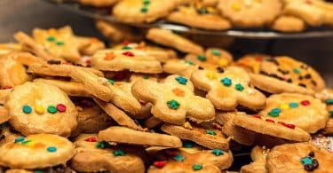 Imagem de duas travessas cheias de cookies todos decorados com açucar de confeiteiro.