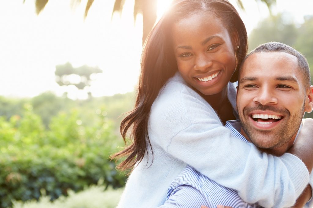 Imagem de um lindo casal afrodescendente, ambos estão lindos, risonhos e felizes.