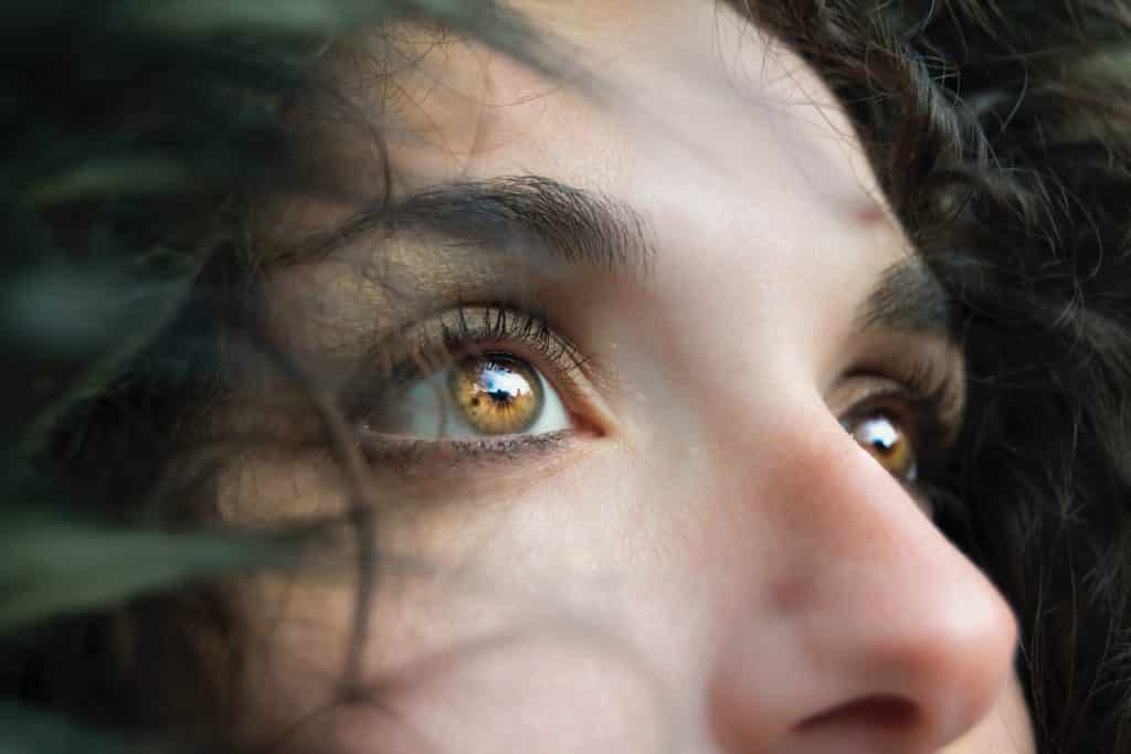 Imagem do olhar pensativo e triste de uma linda mulher de olhos castanhos claros.