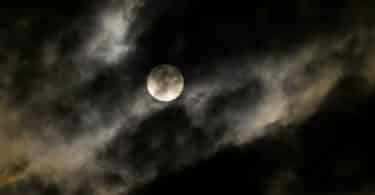 Imagem de um céu encoberto com muitas névoas e ao fundo uma super lua.