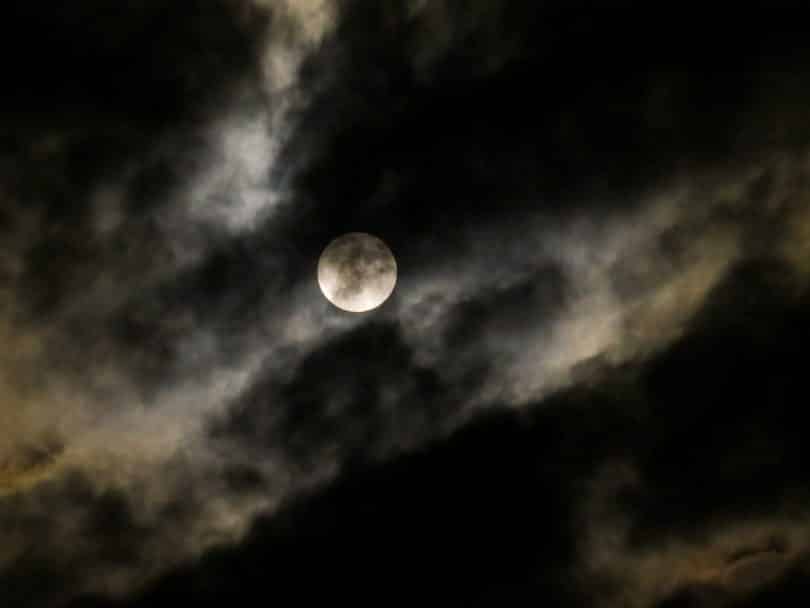 Imagem de um céu encoberto com muitas névoas e ao fundo uma super lua.