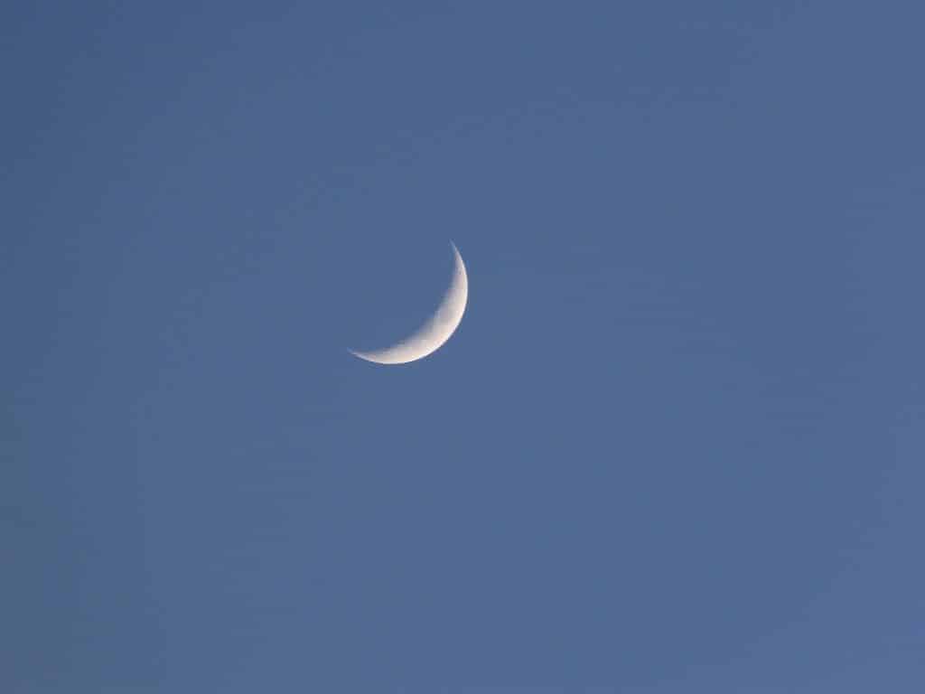 Imagem de cor azul e ao fundo a lua nova na cor branca.
