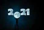 Imagem do ano 2021 desenhando com o fundo da cor da lua. O número zero do ano 2021 está em formato de lua cheia. Um homem está em cima de uma escada e com as mãos segura o número zero em formato de lua.