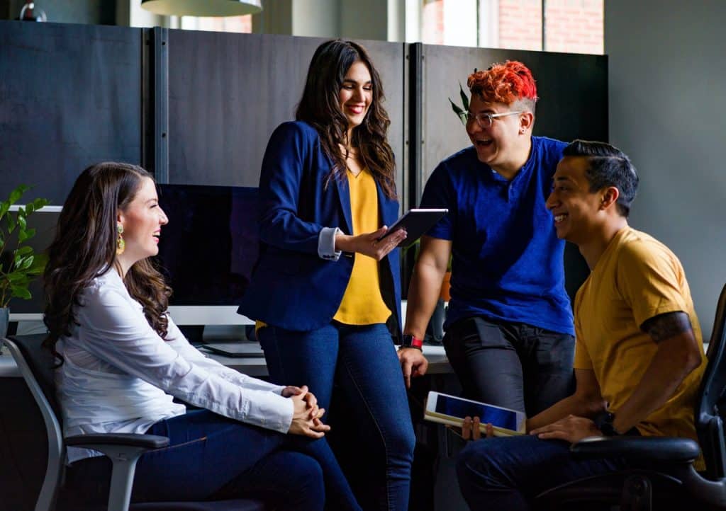 Grupo de quatro jovens em círculo conversando e rindo. 