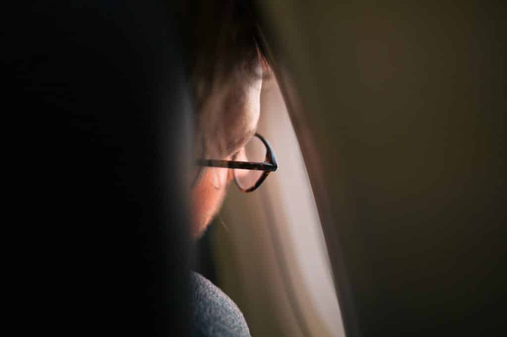 Homem de óculos olhando pela janela de um avião.