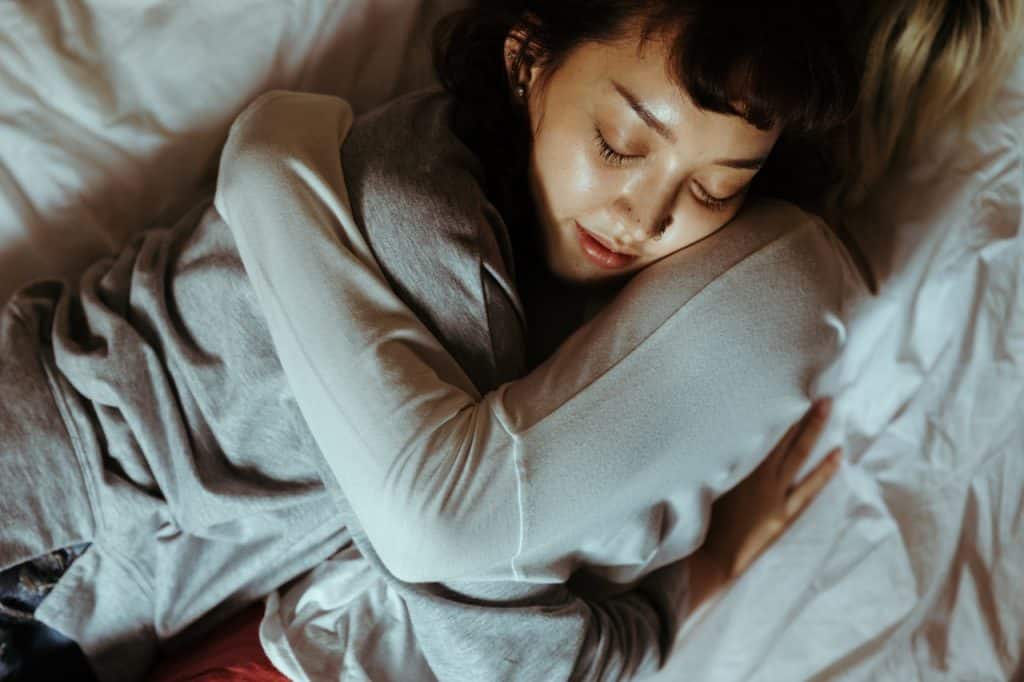 Duas mulheres deitadas na cama abraçadas. 