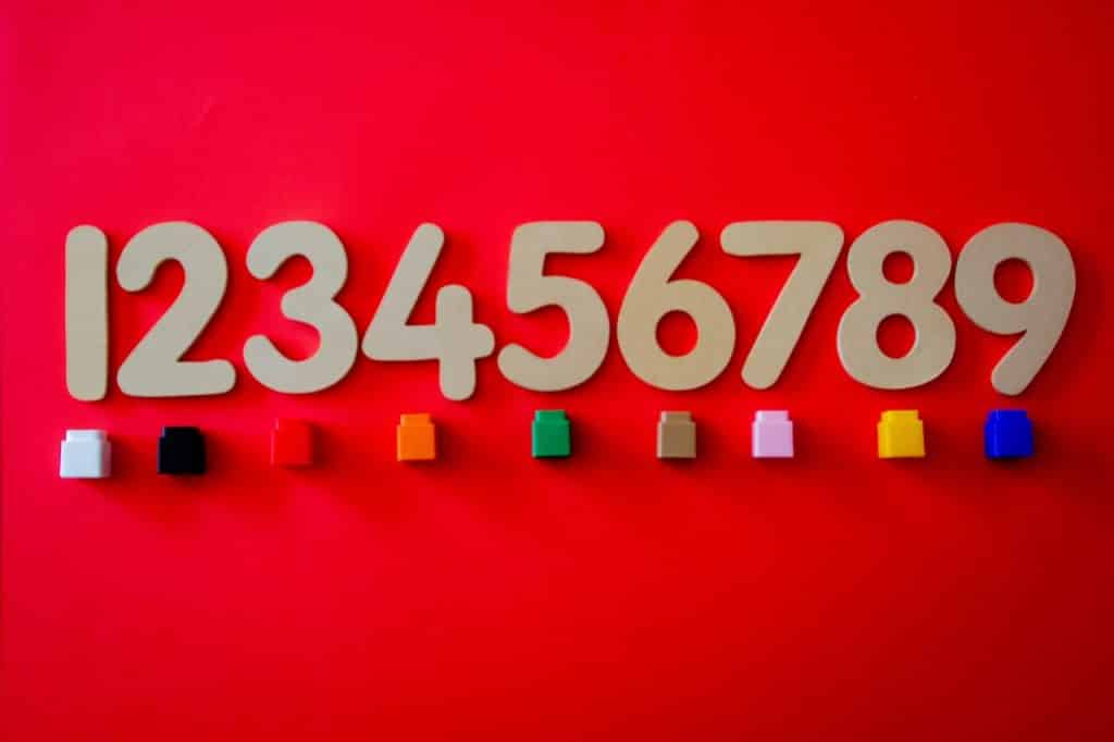 Números de um a nove colocados sobre o fundo vermelho com pedrinhas coloridas embaixo.
