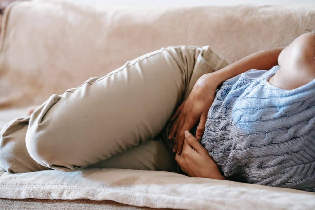 Mulher deitada com dor na barriga