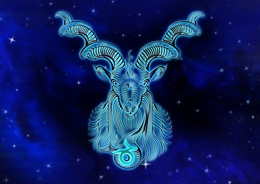 Imagem de fundo azul com alguns pontos de luz. Ao fundo a imagem de um animal mitológico denominado capricornus,  simbolizando o signo de capricórnio.
