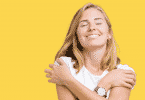 Mulher sorridente no funda amarelo se abraçando