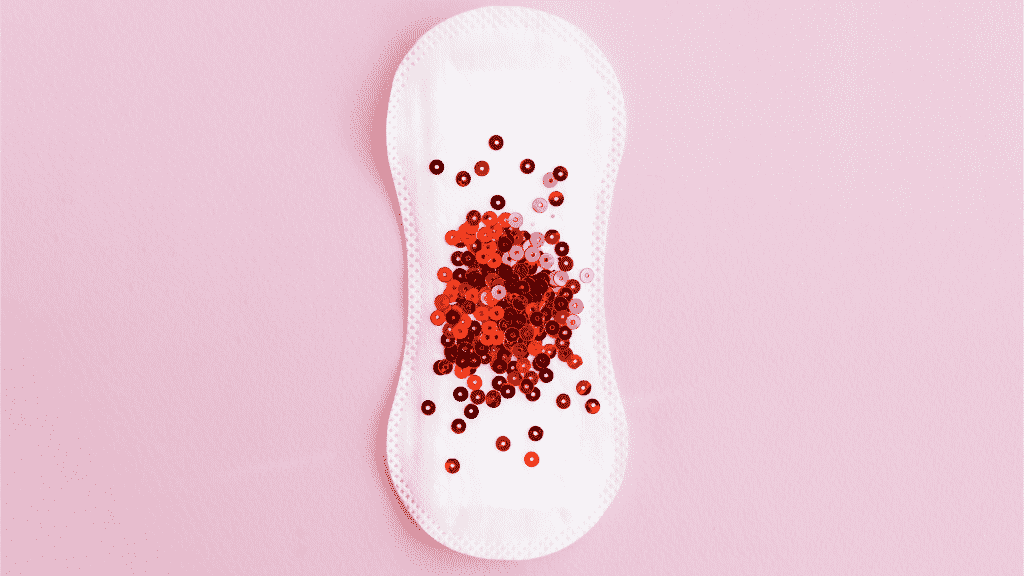 Absorvente com glitter vermelho para representar a menstruação