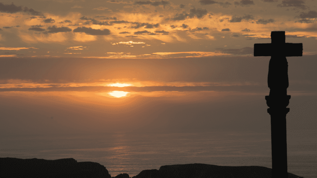 Silhueta de uma cruz em meio o pôr do sol