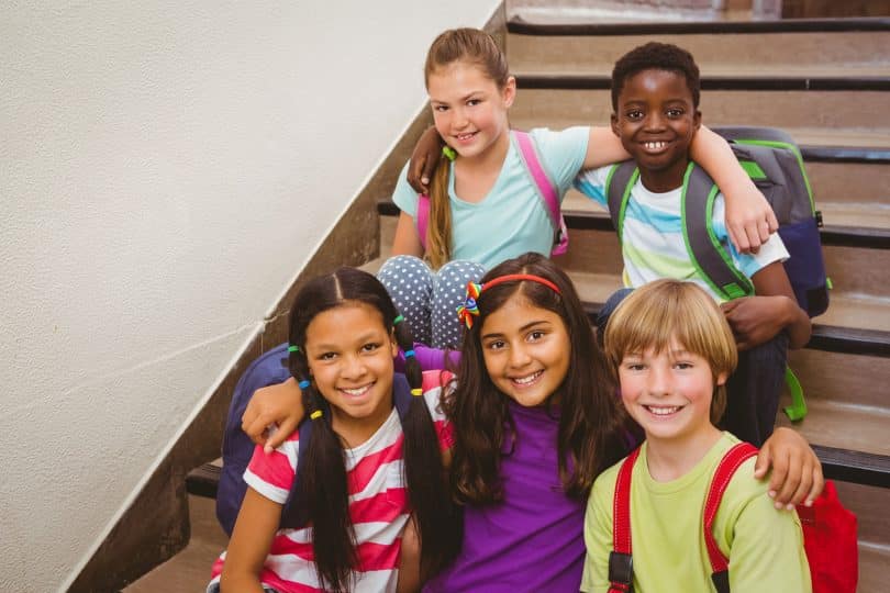 Retrato de alunos sentados na escada da escola.